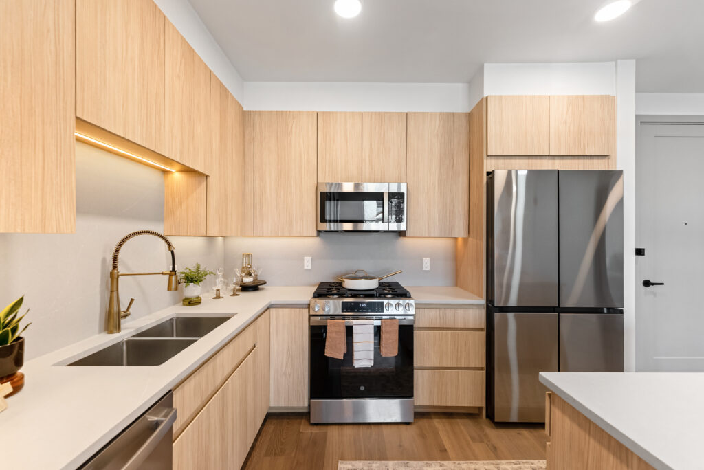 Kitchen in a furnished model home with quartz countertops and light wood cabinets