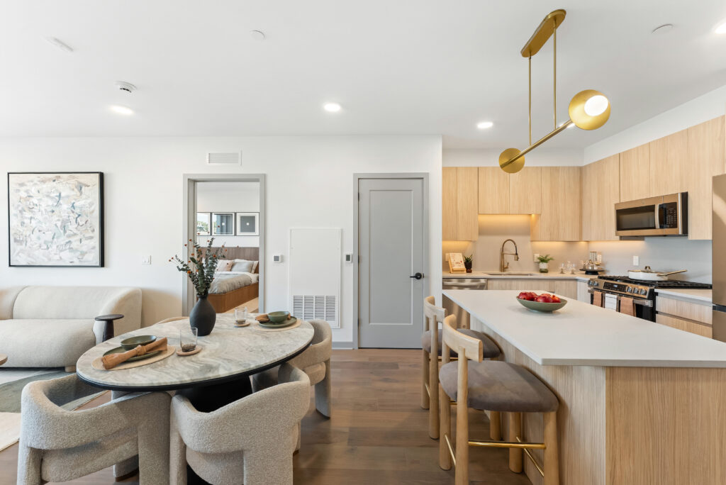 Open kitchen and dining area in a furnished model home, with a round table, pendant light and quartz island